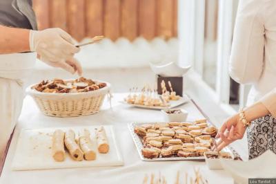 Un kiosque blanc au bord d'un étang avec une fontaine, entouré d'arbres et d'une réception en arrière-plan.