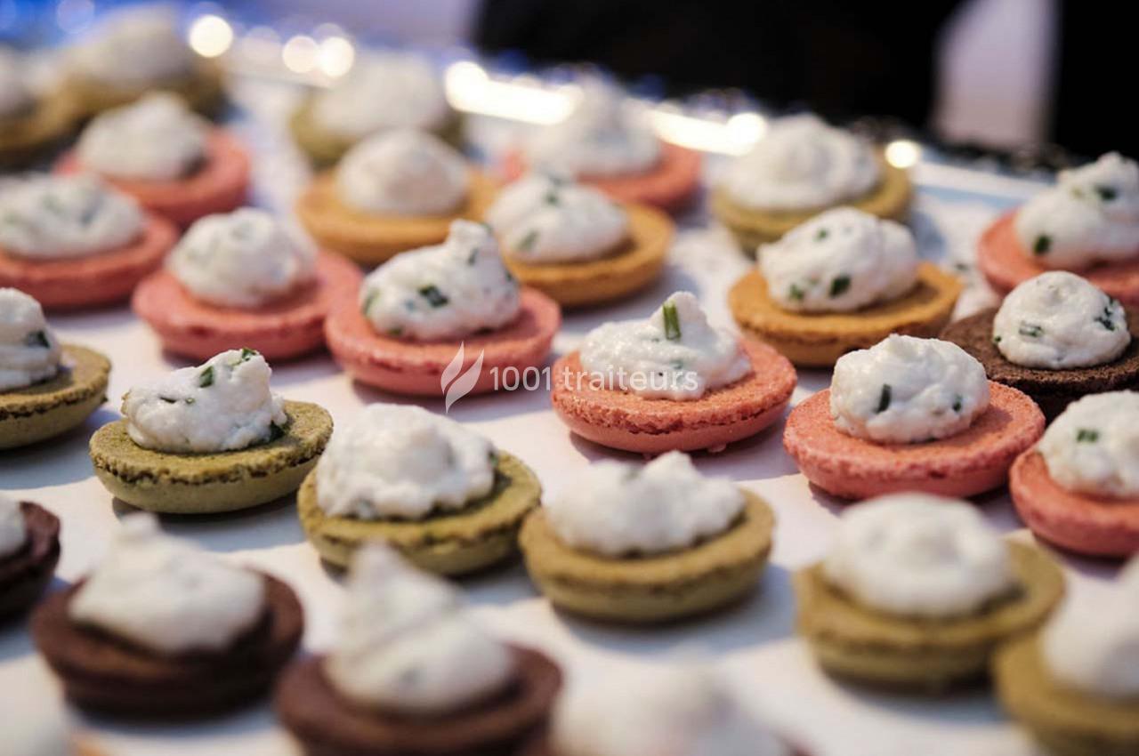 Macarons salés garnis de mousse blanche, présentés sur un plateau lors d'un événement ou d'un buffet.