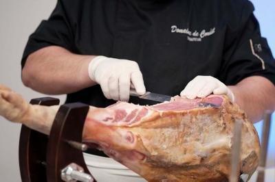 Un kiosque blanc au bord d'un étang avec une fontaine, entouré d'arbres et d'une réception en arrière-plan.