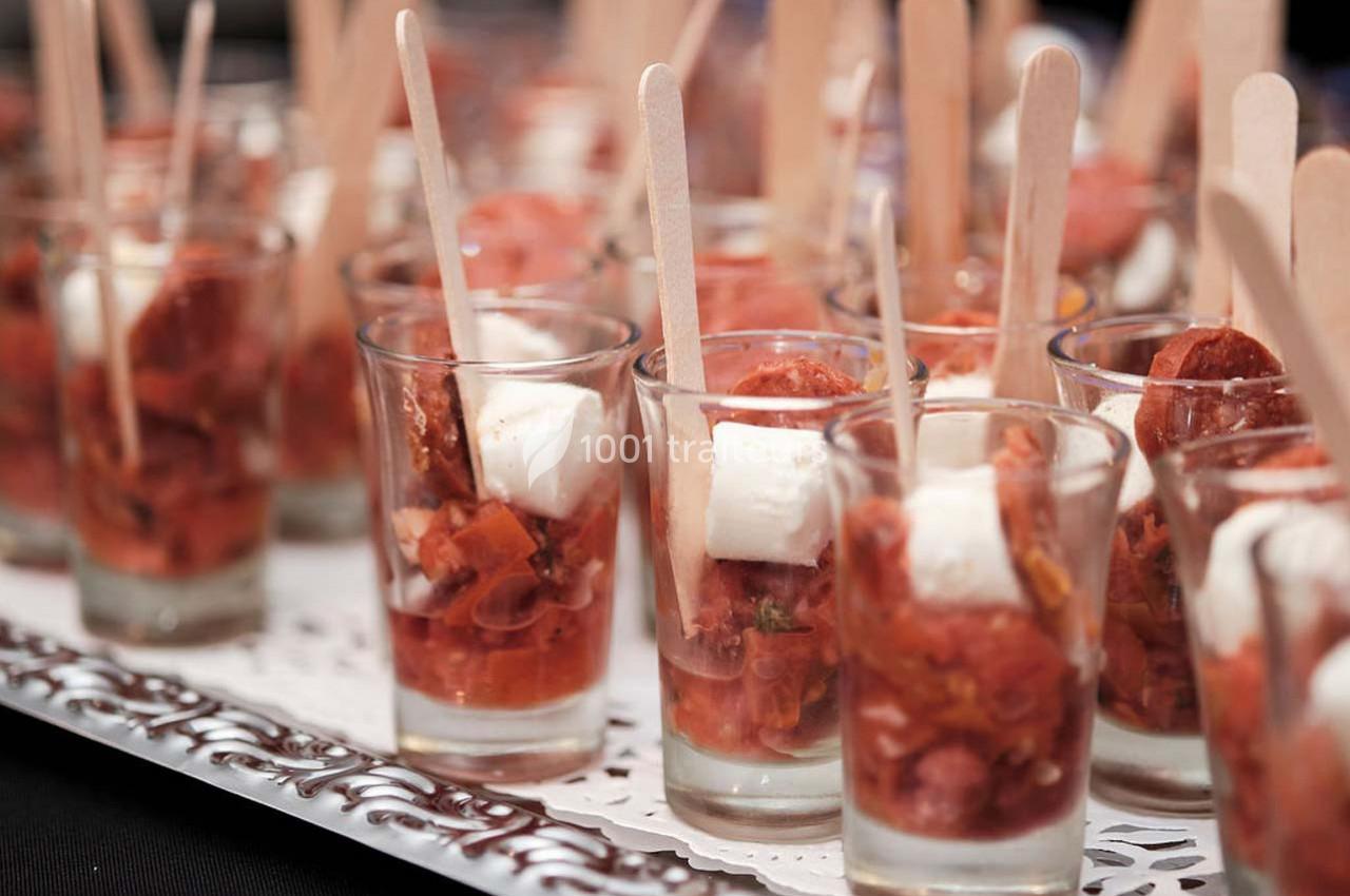 Verrines garnies de dés de fromage, morceaux de chorizo et sauce tomate, présentées avec des bâtonnets en bois.