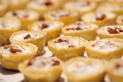Un kiosque blanc au bord d'un étang avec une fontaine, entouré d'arbres et d'une réception en arrière-plan.