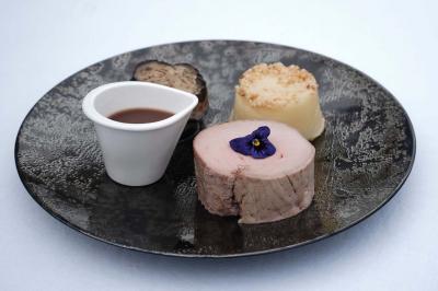 Un kiosque blanc au bord d'un étang avec une fontaine, entouré d'arbres et d'une réception en arrière-plan.