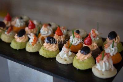 Plateau de canapés variés avec des garnitures salées, disposés de manière symétrique sur une surface métallique.