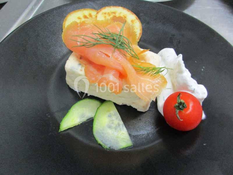 Assiette avec terrine, tranches de saumon fumé, rondelles de concombre, tomate cerise et crème décorée d'aneth.