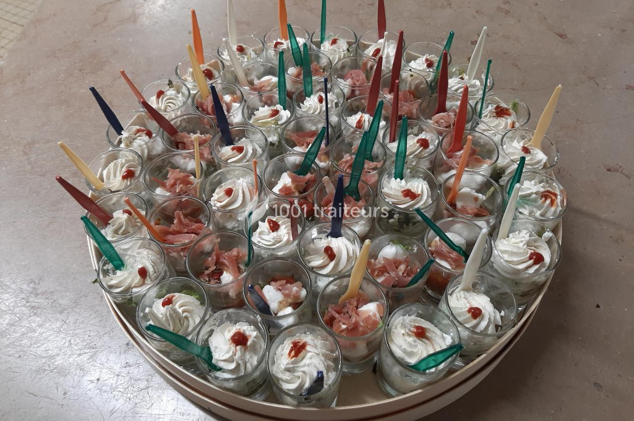 Plateau de verrines apéritives garnies de crème, saumon et décorées avec des cuillères colorées.