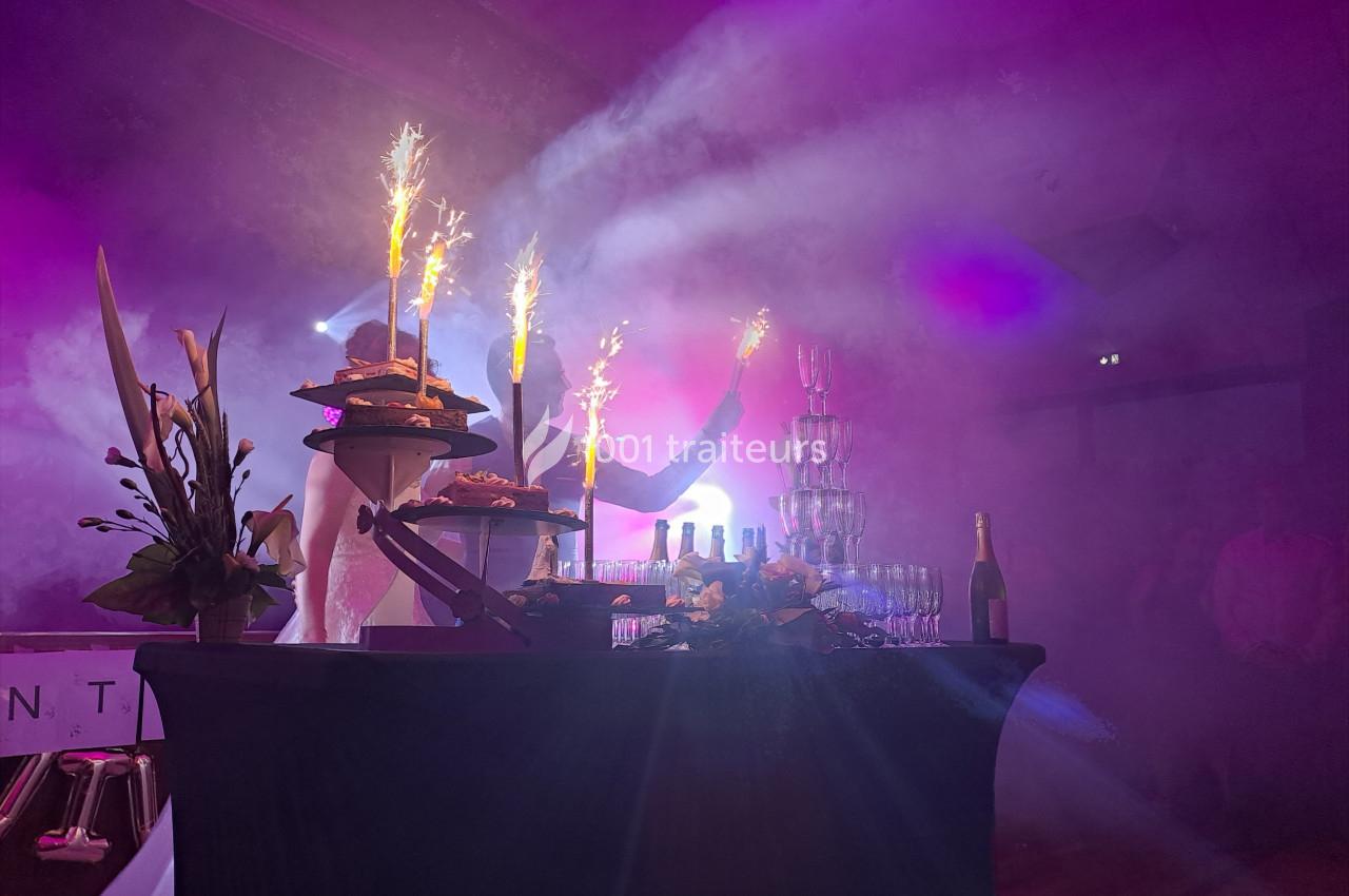 Table décorée avec des desserts, des coupes empilées, des bouteilles et des feux d'artifice dans une ambiance lumineuse et…