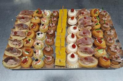 Plateau de canapés variés avec des garnitures salées, disposés de manière symétrique sur une surface métallique.