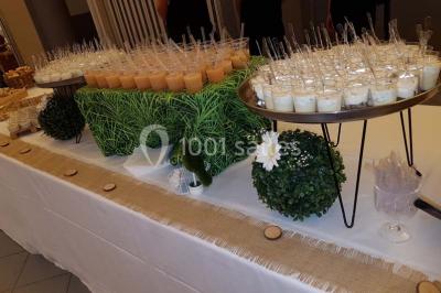 Tour de choux décorée avec des fleurs et des étincelles, entourée de desserts sur une table de réception.