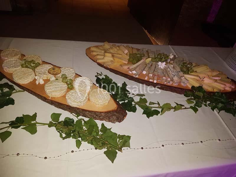 Plateaux de fromages variés avec raisins verts, présentés sur des planches en bois décorées de feuillage.