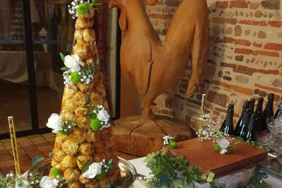 Tour de choux décorée avec des fleurs et des étincelles, entourée de desserts sur une table de réception.