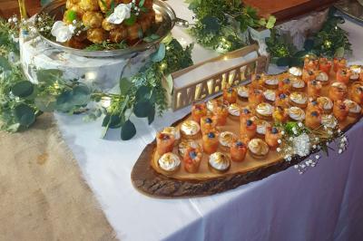 Tour de choux décorée avec des fleurs et des étincelles, entourée de desserts sur une table de réception.