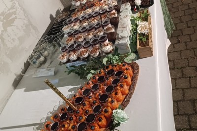 Un camion de traiteur avec des illustrations culinaires, accompagné de personnes préparant et servant des plats.