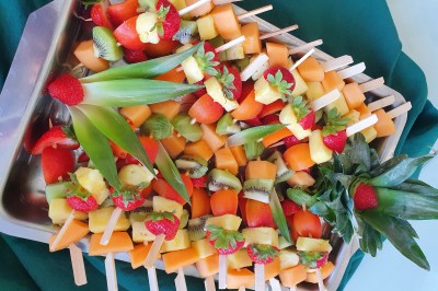 Un camion de traiteur avec des illustrations culinaires, accompagné de personnes préparant et servant des plats.