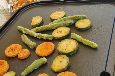 Un camion de traiteur avec des illustrations culinaires, accompagné de personnes préparant et servant des plats.