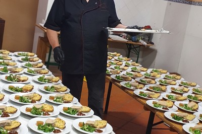 Un camion de traiteur avec des illustrations culinaires, accompagné de personnes préparant et servant des plats.