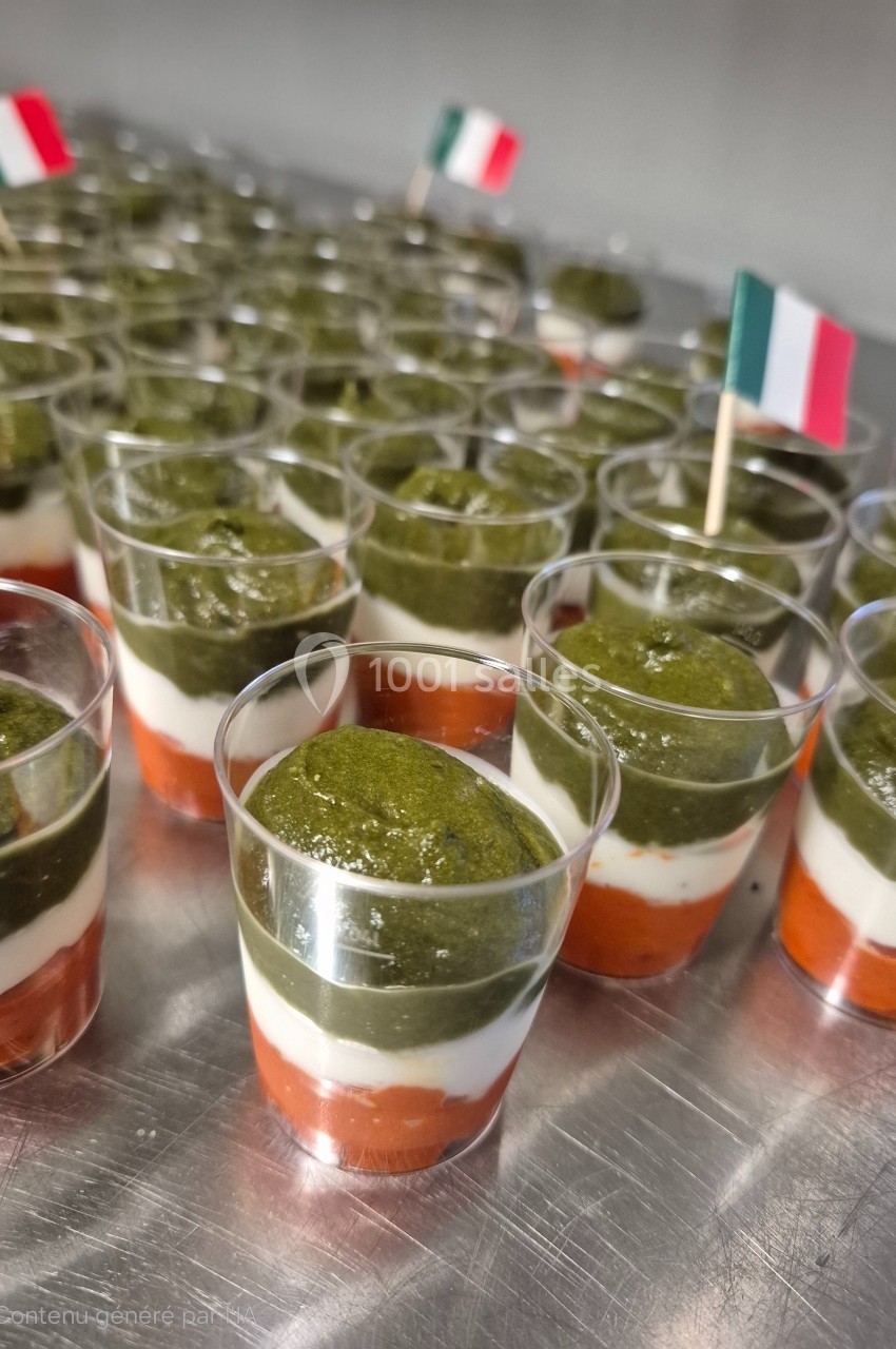 Verrines tricolores avec couches de tomate, mozzarella et pesto, décorées de petits drapeaux italiens.