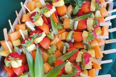 Un camion de traiteur avec des illustrations culinaires, accompagné de personnes préparant et servant des plats.