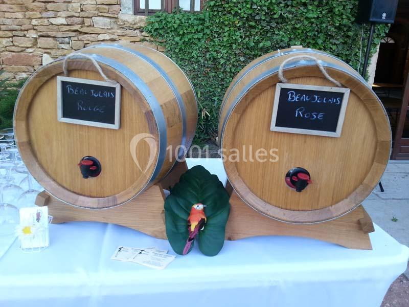 Deux tonneaux en bois étiquetés ’Beaujolais Rouge’ et ’Beaujolais Rosé’ posés sur une table blanche, décorés d'une feuille…