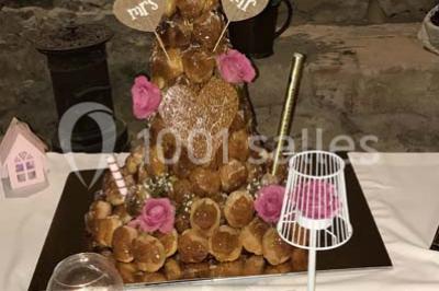 Tour de choux décorée avec des fleurs et des étincelles, entourée de desserts sur une table de réception.
