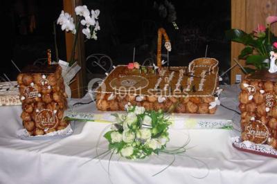 Tour de choux décorée avec des fleurs et des étincelles, entourée de desserts sur une table de réception.