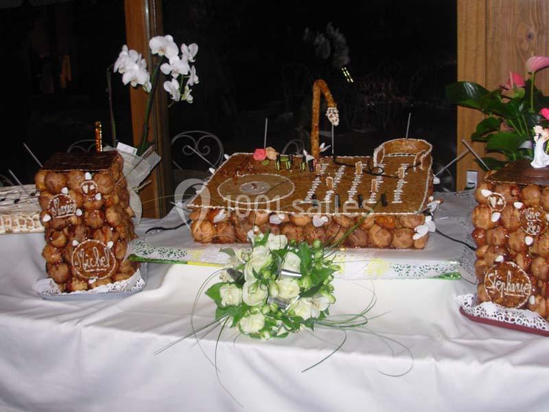 Pièce montée en forme de platine DJ avec des détails en pâte à choux et caramel, entourée de fleurs blanches.