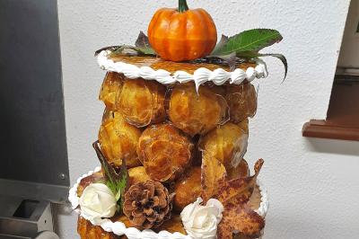 Tour de choux décorée avec des fleurs et des étincelles, entourée de desserts sur une table de réception.