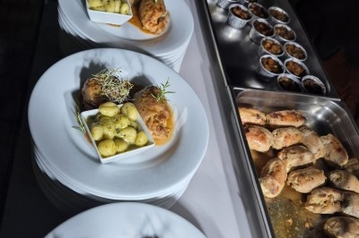 Buffet d'anniversaire en extérieur avec nappes blanches, plats variés, boissons et décor champêtre.