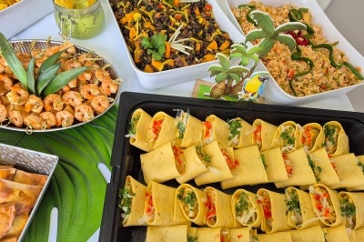 Buffet d'anniversaire en extérieur avec nappes blanches, plats variés, boissons et décor champêtre.