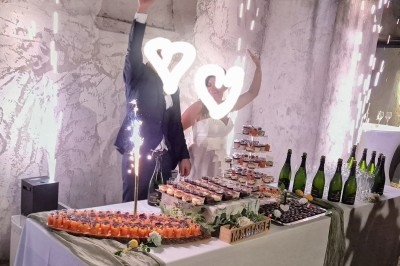 Buffet d'anniversaire en extérieur avec nappes blanches, plats variés, boissons et décor champêtre.