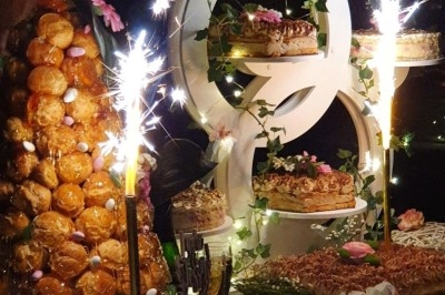 Buffet d'anniversaire en extérieur avec nappes blanches, plats variés, boissons et décor champêtre.