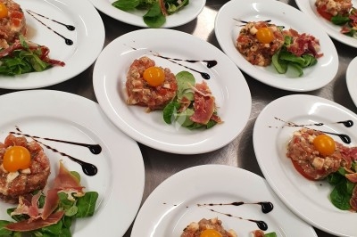 Buffet d'anniversaire en extérieur avec nappes blanches, plats variés, boissons et décor champêtre.