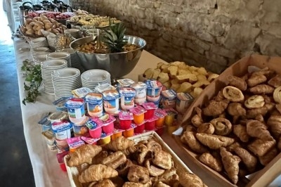 Buffet d'anniversaire en extérieur avec nappes blanches, plats variés, boissons et décor champêtre.