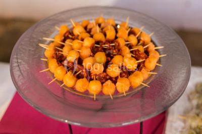 Fontaine à chocolat sur une table de buffet avec des fruits frais et des brochettes en arrière-plan.