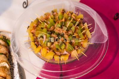 Fontaine à chocolat sur une table de buffet avec des fruits frais et des brochettes en arrière-plan.