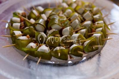 Fontaine à chocolat sur une table de buffet avec des fruits frais et des brochettes en arrière-plan.