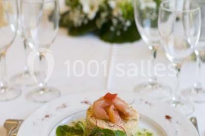 Fontaine à chocolat sur une table de buffet avec des fruits frais et des brochettes en arrière-plan.