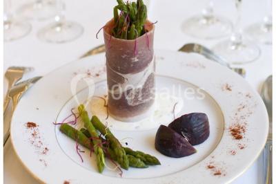 Fontaine à chocolat sur une table de buffet avec des fruits frais et des brochettes en arrière-plan.