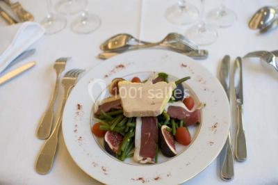 Fontaine à chocolat sur une table de buffet avec des fruits frais et des brochettes en arrière-plan.