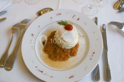 Fontaine à chocolat sur une table de buffet avec des fruits frais et des brochettes en arrière-plan.