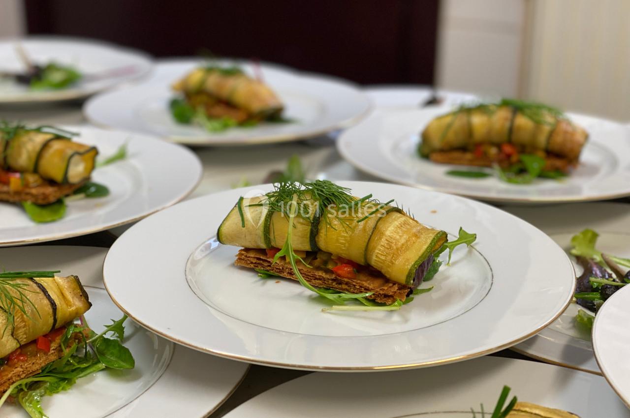 Assiette garnie de rouleaux de courgettes farcies, posés sur un lit de légumes et accompagnés de verdure fraîche.