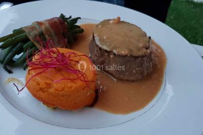 Fontaine à chocolat sur une table de buffet avec des fruits frais et des brochettes en arrière-plan.