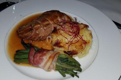 Fontaine à chocolat sur une table de buffet avec des fruits frais et des brochettes en arrière-plan.