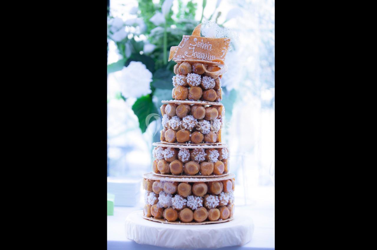 Pièce montée de choux garnis de crème, décorée de sucre et d'une plaque en caramel, posée sur un présentoir.
