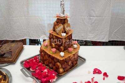 Gâteau au chocolat décoré de framboises et d'une fleur rose, présenté sur un plateau sombre.