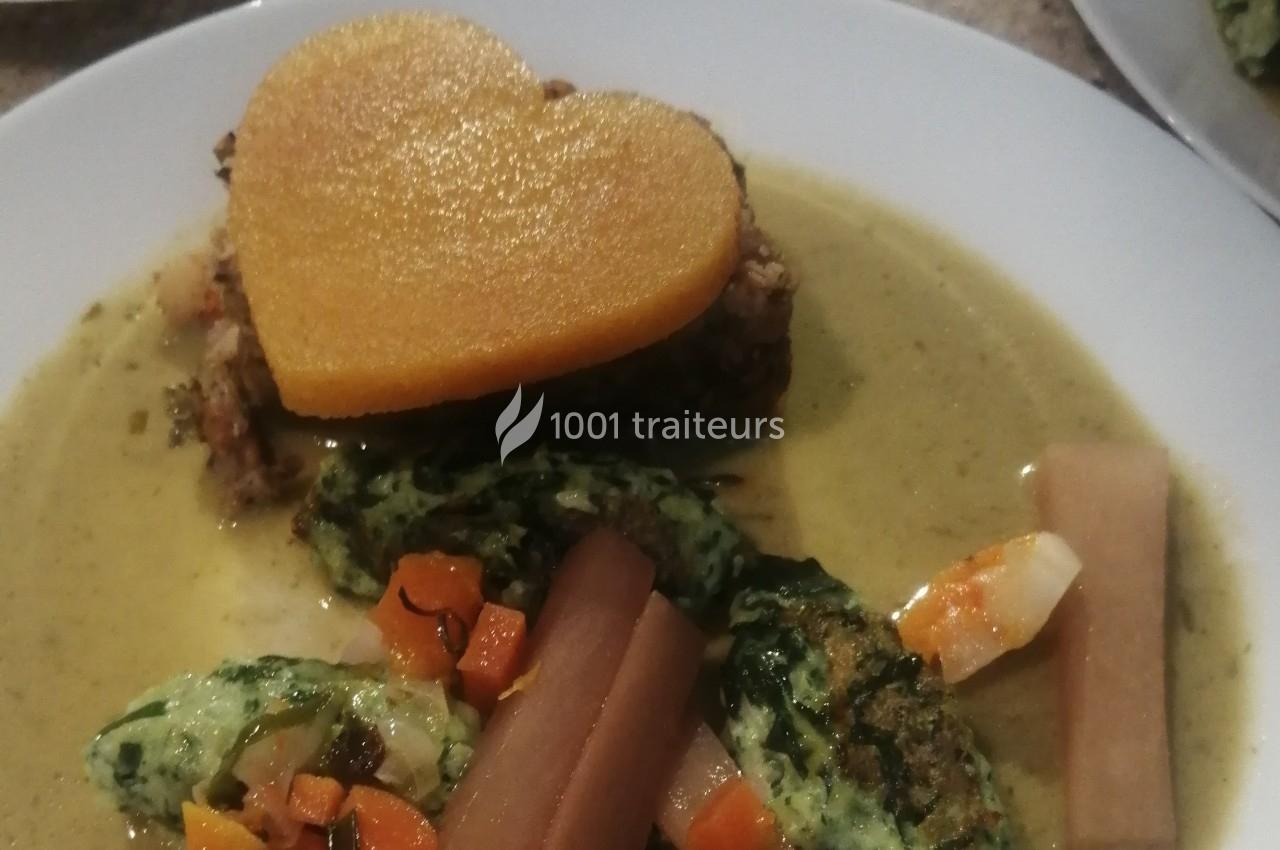Assiette contenant un plat composé de légumes, quenelles vertes et une tranche en forme de cœur sur une sauce.