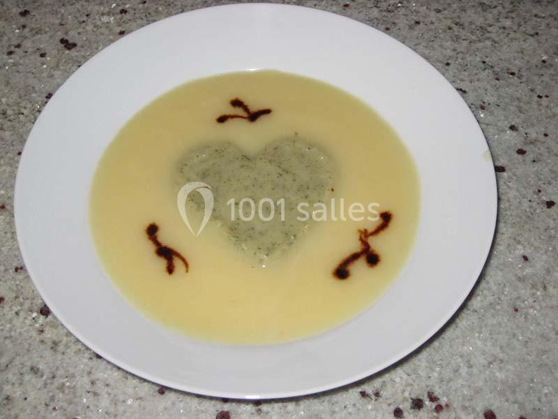 Assiette de soupe beige avec un motif en forme de cœur vert au centre et des décorations brunes autour.