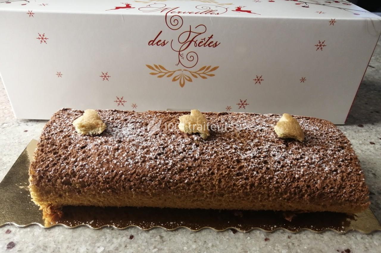 Bûche de Noël décorée de biscuits en forme d'étoiles, posée devant une boîte festive blanche.