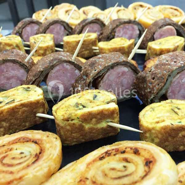Assortiment de bouchées apéritives comprenant roulés feuilletés, omelettes roulées et morceaux de saucisse en croûte.