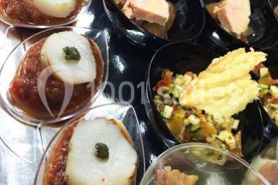 Plateau à étages avec des coquilles garnies de crevettes, légumes et herbes, présenté sur une table de buffet.