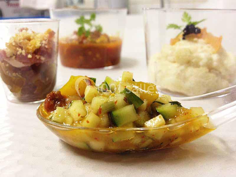 Assortiment de verrines et cuillères apéritives contenant des préparations variées à base de légumes et condiments.